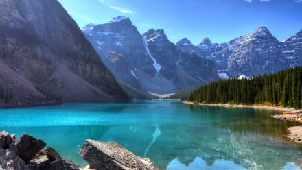 A stunning view of Moraine Lake in Banff National Park, Alberta, Canada, featuring clear turquoise water reflecting towering cliffs and snow-capped peaks of the Canadian Rockies.