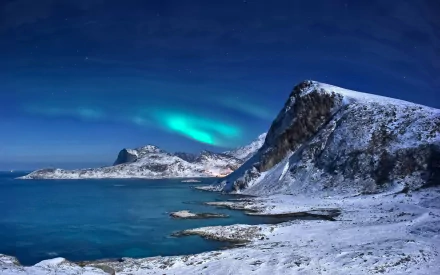 A stunning HD desktop wallpaper showcasing a snow-covered mountain landscape under a vibrant aurora borealis, reflecting beautifully on the tranquil sea.