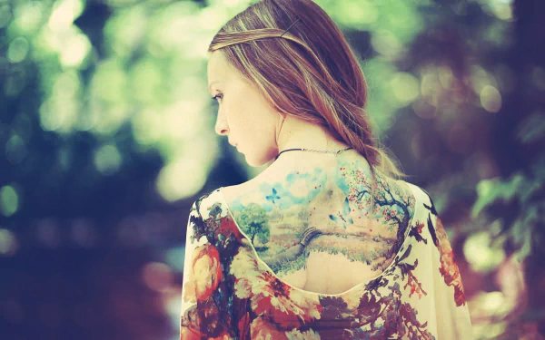 HD desktop wallpaper featuring a woman with an intricate tattoo on her back, set against a softly blurred natural background.