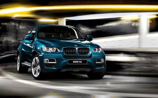 HD PC desktop wallpaper featuring a sleek blue BMW X6 vehicle captured in motion with a dynamic blurred city background.