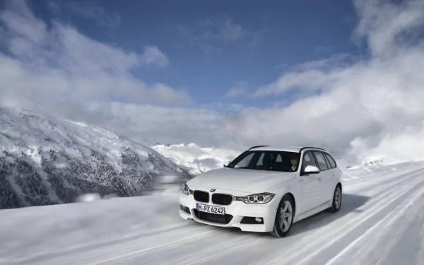 White 2013 BMW 320d on a snow-covered mountain road under blue sky — HD PC desktop wallpaper and background showing a crisp winter landscape.
