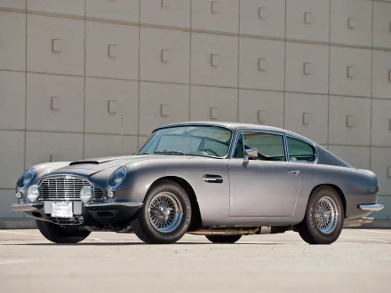 Aston Martin DB6 parked against a beige wall, showcased in a high-definition PC desktop wallpaper and background.