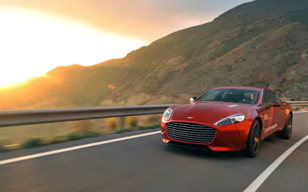Red Aston Martin Rapide driving on a winding mountain road at sunset — 2K Quad HD PC desktop wallpaper of an Aston Martin vehicle.