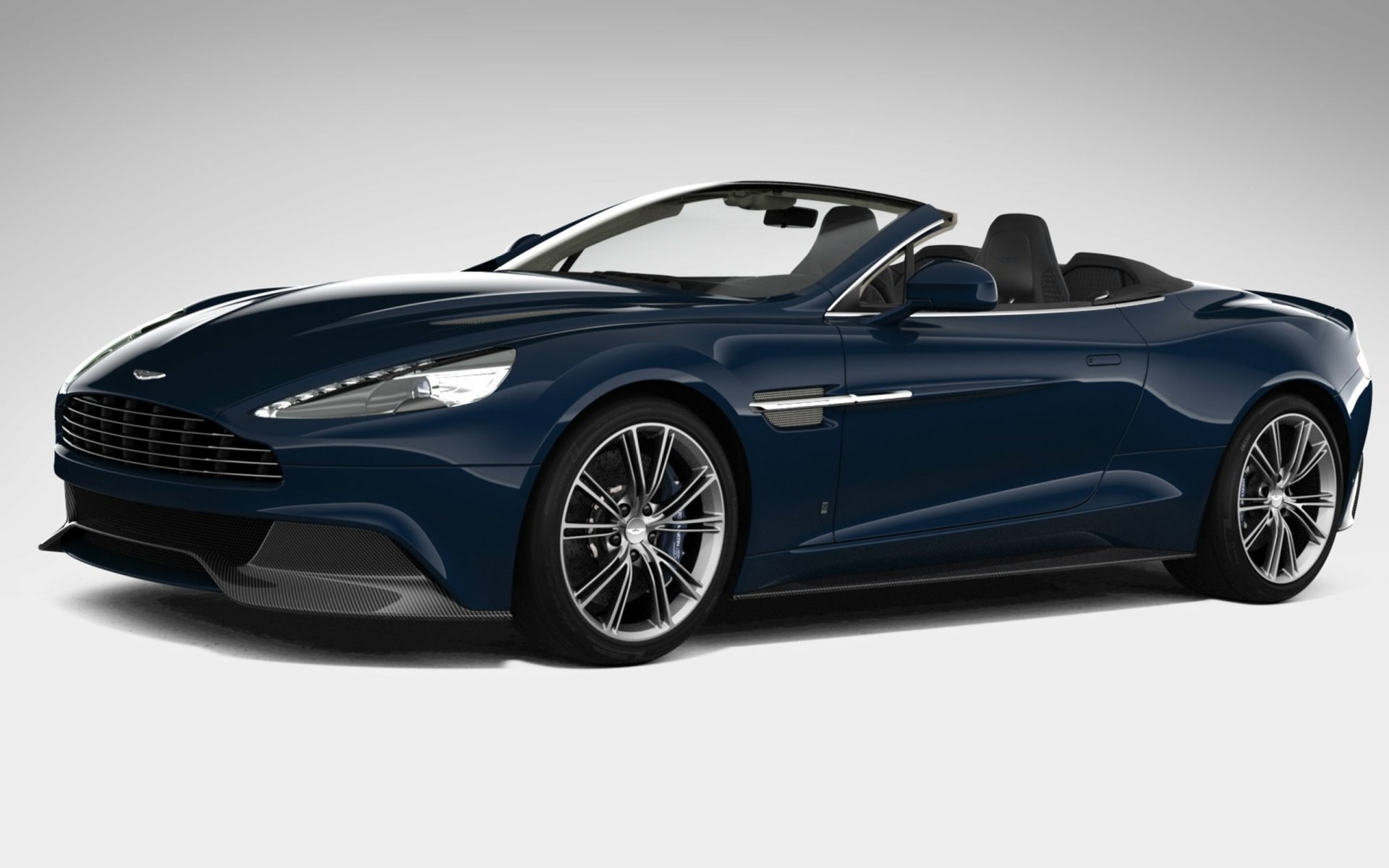 HD PC desktop wallpaper featuring a sleek dark blue Aston Martin Vanquish Volante convertible sports car against a plain background.