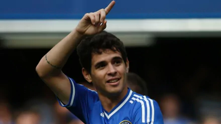 HD PC desktop sports wallpaper of a smiling male soccer player in a blue kit raising a finger in celebration; image tagged with a player name, identity withheld.