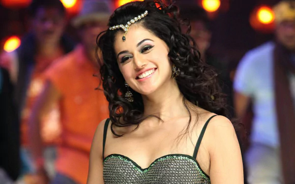 Brunette Bollywood actress Taapsee Pannu smiles radiantly, captured in a vibrant scene with a lively background, showcasing her charm and charisma. HD desktop wallpaper.