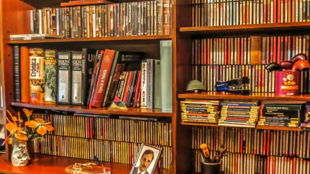 HD PC desktop wallpaper featuring a man-made library with wooden shelves filled with books, CDs, and decorative items, showcasing a cozy and organized reading space.