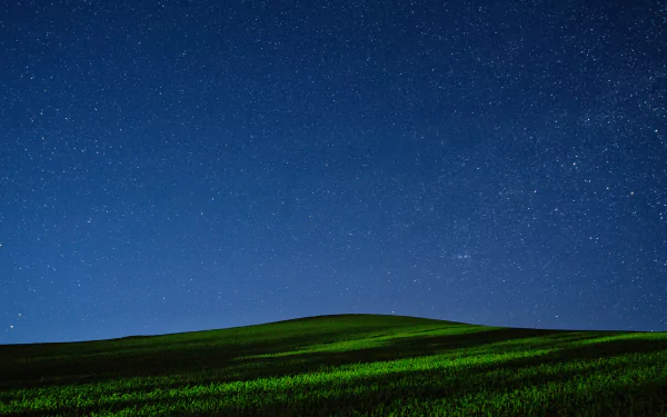 4K Ultra HD sci‑fi PC desktop wallpaper: green rolling hill beneath a vast star-filled night sky, faint Milky Way band — tranquil cosmic background.