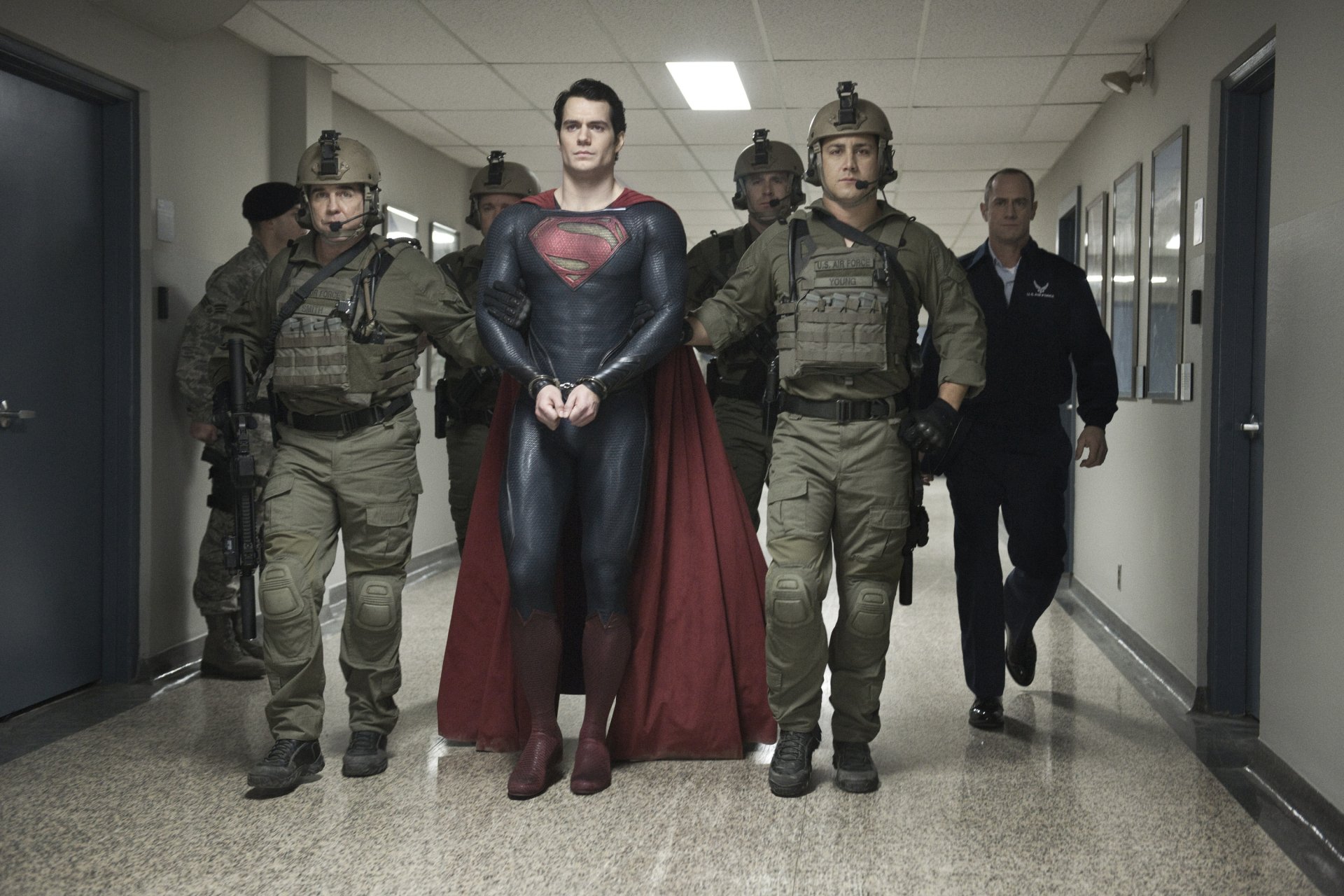 HD PC desktop wallpaper featuring Henry Cavill as Superman in his Man of Steel costume, walking confidently down a hallway flanked by soldiers.