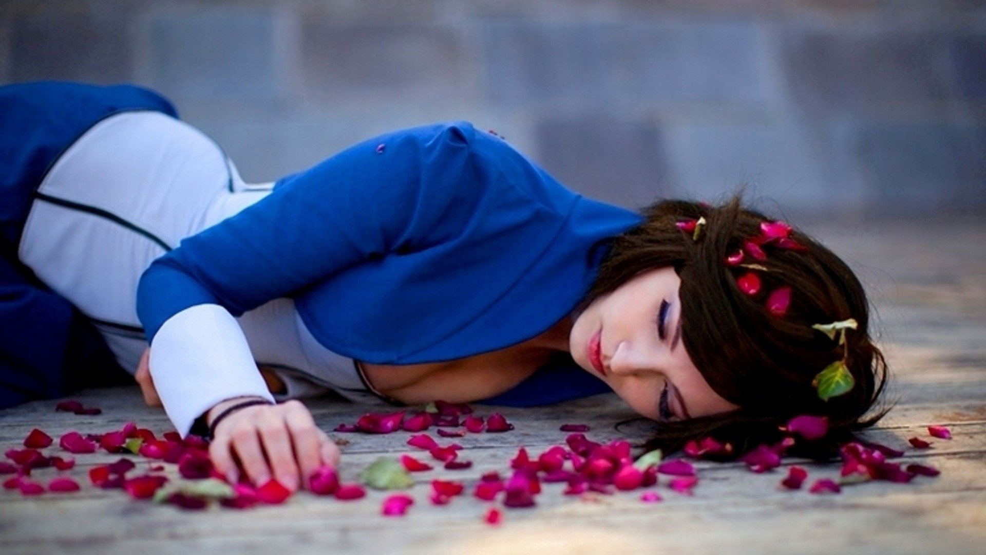 A character from Bioshock Infinite lies on the ground surrounded by rose petals, captured in a HD PC desktop wallpaper that evokes a poignant, atmospheric mood.