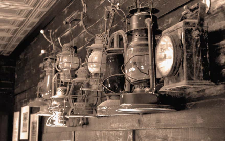 A row of old man-made lanterns and torches hanging against a wooden wall, captured in a sepia-toned HD desktop wallpaper.