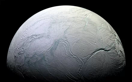 HD PC desktop wallpaper/background: Sci‑Fi view of Enceladus, Saturn's icy moon, showing cracked, ridged surface and curved limb against deep black space.