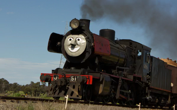HD PC desktop wallpaper of a steam train locomotive with a cheerful face, billowing smoke and carriages rolling along rural tracks under a clear blue sky.