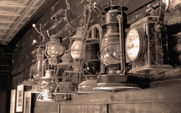 A row of old man-made lanterns and torches hanging against a wooden wall, captured in a sepia-toned HD desktop wallpaper.