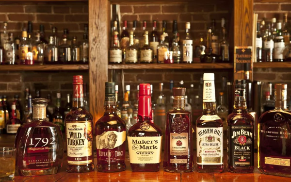 A vibrant selection of whisky bottles displayed on a wooden bar, with a rich backdrop of shelves filled with various spirits, creating an inviting atmosphere for food and drink lovers.