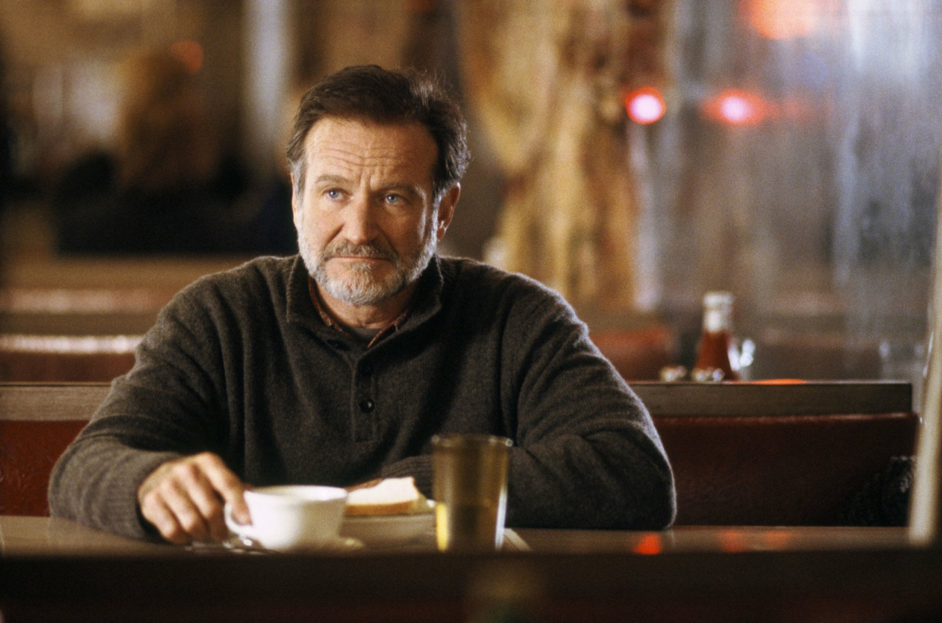 HD desktop wallpaper featuring Robin Williams in a scene from The Night Listener, sitting pensively in a diner.
