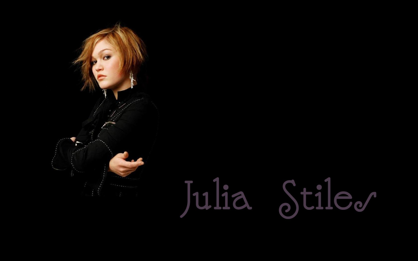 A striking HD wallpaper featuring actress Julia Stiles, showcasing her confident pose against a dark background, highlighted by elegant text displaying her name.