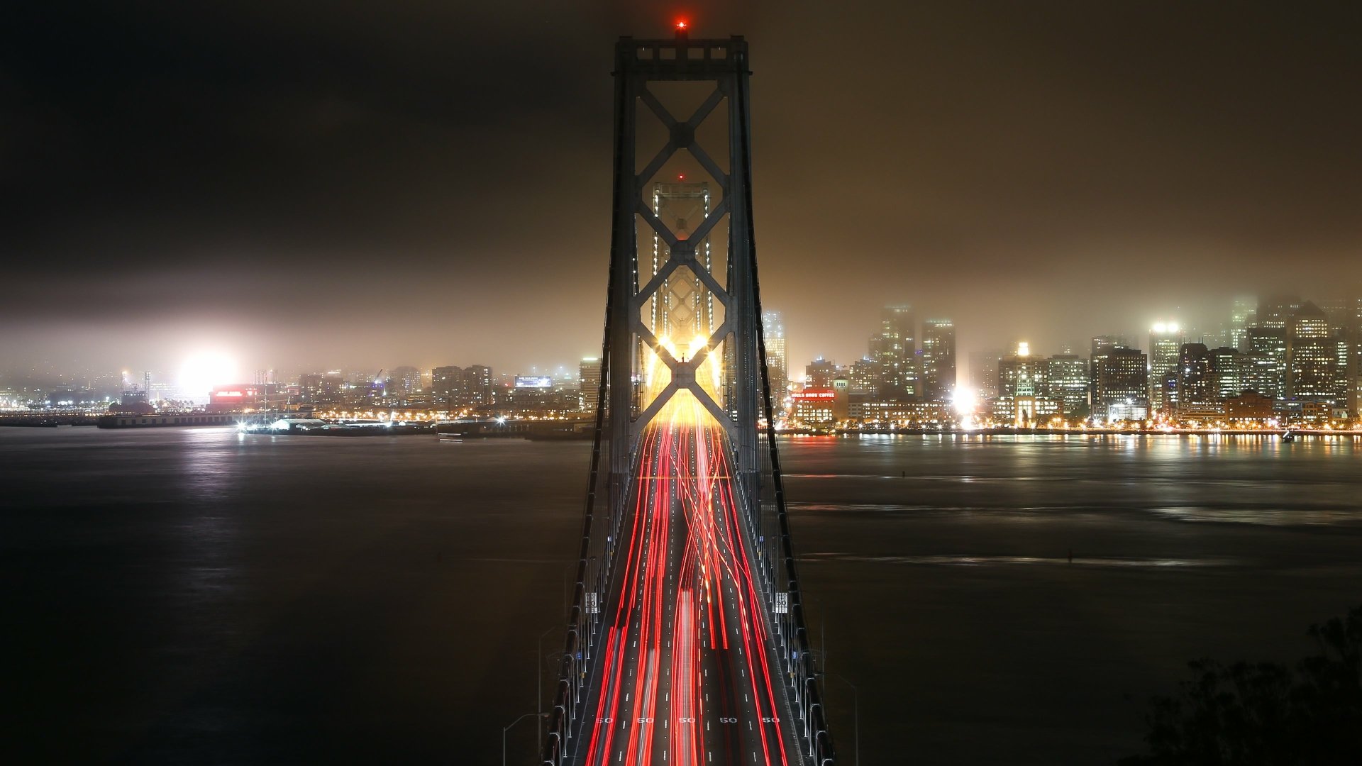 Night view of the Willie Brown Bridge, part of the San Francisco Bay Bridge, with city lights and light trails captured in 4K Ultra HD quality.