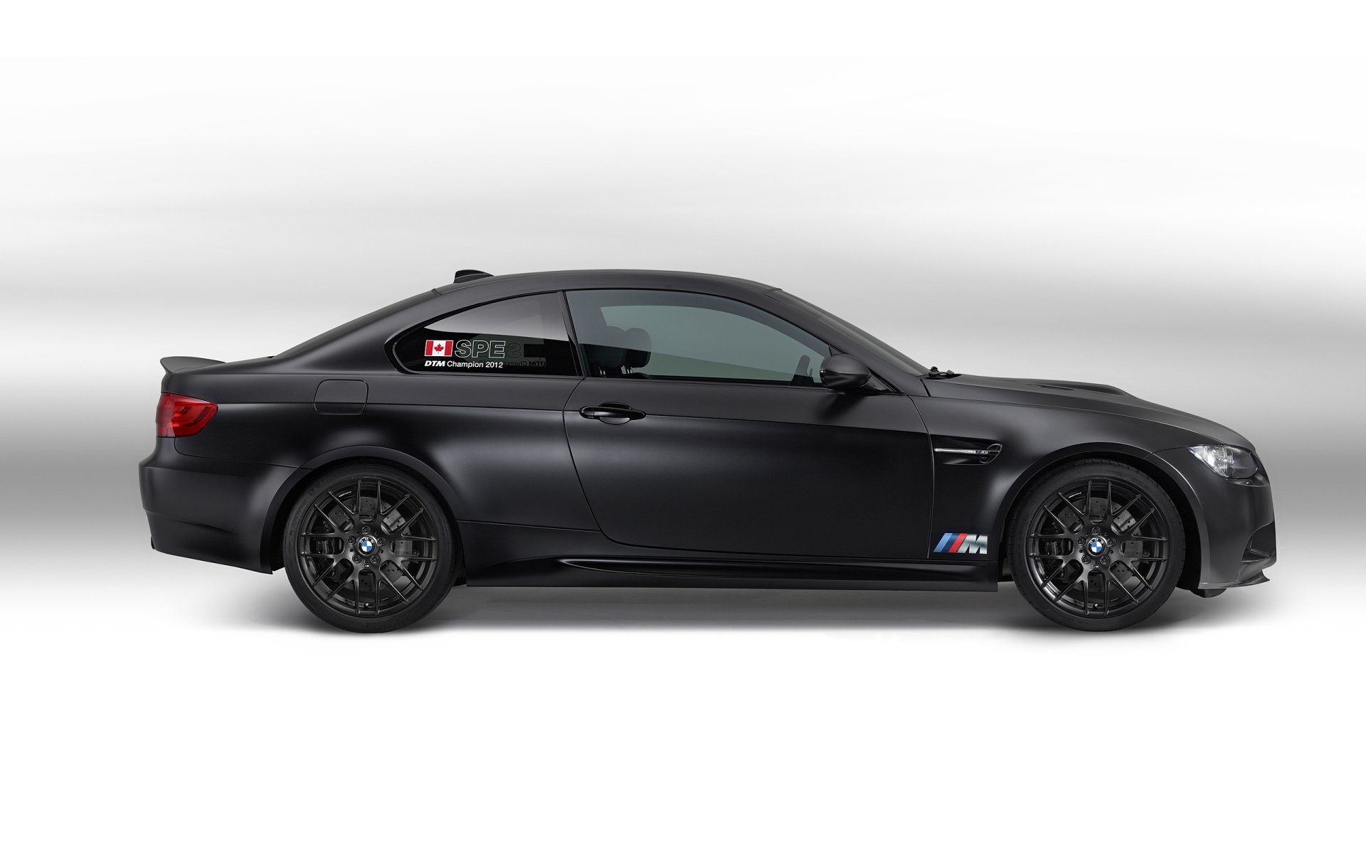 HD desktop wallpaper featuring a sleek black BMW M3 DTM vehicle in profile against a clean white background.