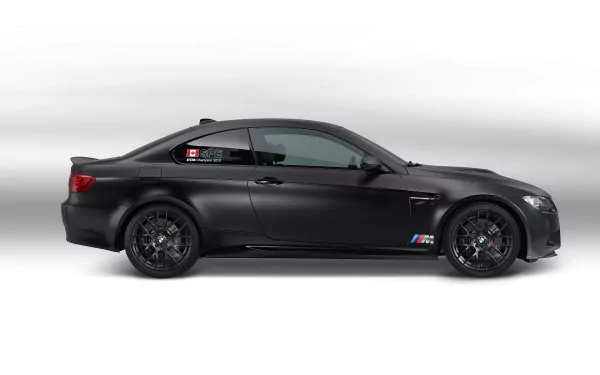 HD desktop wallpaper featuring a sleek black BMW M3 DTM vehicle in profile against a clean white background.
