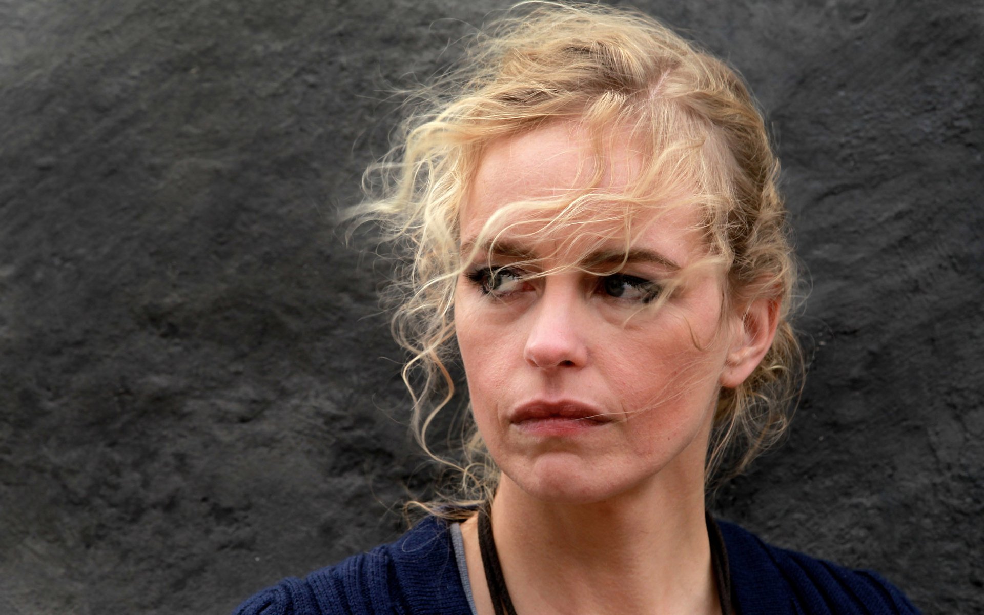 HD desktop wallpaper featuring German actress Nina Hoss with a contemplative expression against a dark textured background.