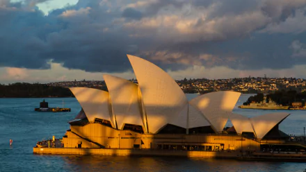 Sydney Opera House in warm sunlight against a dramatic sky, captured in 4K Ultra HD as a striking man-made architectural landmark and desktop wallpaper.