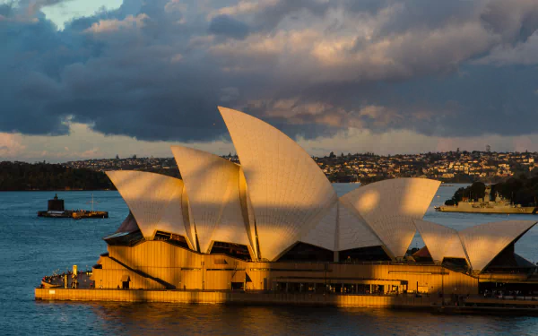 Sydney Opera House in warm sunlight against a dramatic sky, captured in 4K Ultra HD as a striking man-made architectural landmark and desktop wallpaper.