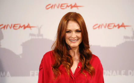 HD desktop wallpaper featuring British actress and celebrity Julianne Moore smiling in a red outfit against a cinema-themed backdrop.