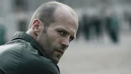 HD wallpaper featuring Jason Statham from the movie Death Race, showcasing a dramatic moment as he looks back with an intense expression in a gritty prison setting.
