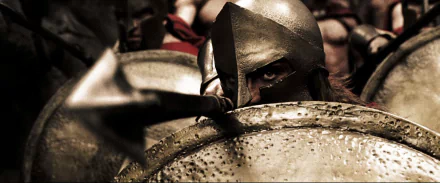 A dramatic HD wallpaper from the movie 300, featuring a fierce Spartan warrior in battle armor, showcasing intense expression and historical atmosphere.