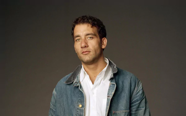 HD PC desktop wallpaper featuring English actor and celebrity Clive Owen against a plain dark background, dressed in a denim jacket over a white shirt.