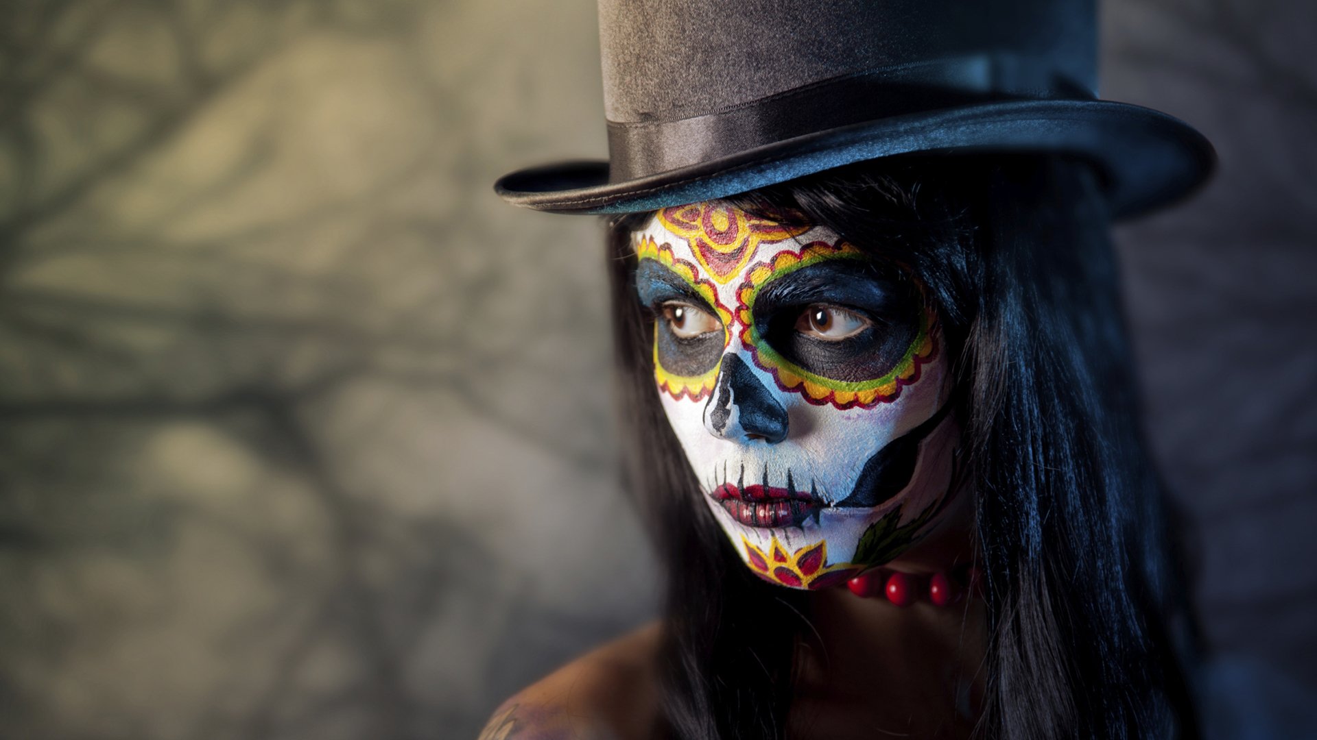 HD wallpaper of a person wearing a sugar skull makeup and top hat, artistically captured against a blurred background.