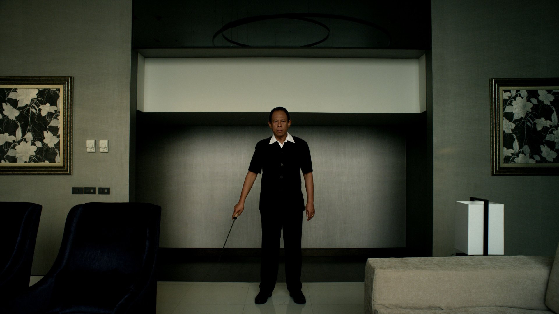 Vithaya Pansringarm from the movie Only God Forgives stands centered in a dimly lit modern room, holding a weapon in this 4K Ultra HD PC desktop wallpaper.