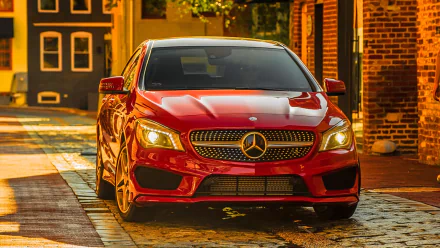 HD PC desktop wallpaper featuring a red Mercedes-Benz CLA-Class parked on a cobblestone street with warm lighting and brick buildings in the background.