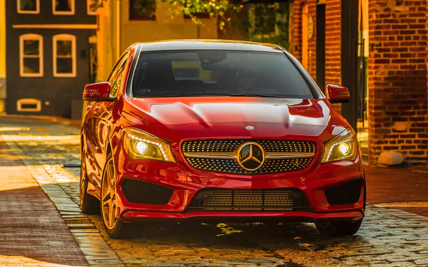 HD PC desktop wallpaper featuring a red Mercedes-Benz CLA-Class parked on a cobblestone street with warm lighting and brick buildings in the background.