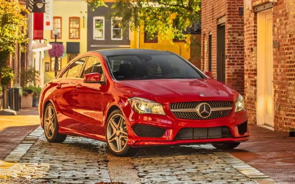 HD PC desktop wallpaper featuring a red Mercedes-Benz CLA-Class parked on a sunlit cobblestone street in an urban setting.