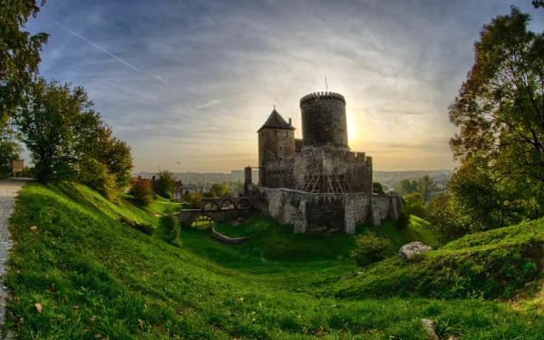 Man-made Bedzin Castle on a grassy hill at sunset, dramatic sky and stone towers, HD PC desktop wallpaper and background with panoramic high-definition detail.