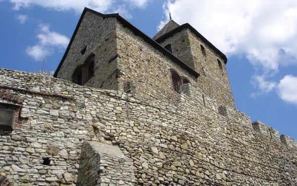 HD PC desktop wallpaper of man-made Bedzin Castle: towering stone walls, arched openings and a crenellated tower beneath a bright blue sky.