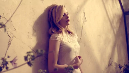 A striking HD desktop wallpaper featuring Chloë Grace Moretz, leaning against a textured wall, her expression contemplative amid delicate floral accents.
