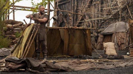 Bearded man in rugged biblical costume assembles a shelter on a shoreline in a scene from the movie Noah — HD PC desktop wallpaper and background.