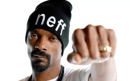 A high-definition desktop wallpaper featuring Snoop Dogg, showcasing him in a black beanie and striking a confident pose with a raised fist.