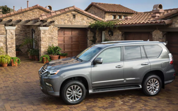 HD PC desktop wallpaper/background: silver Lexus GX vehicle parked on a cobblestone driveway in front of a stone Mediterranean-style house.
