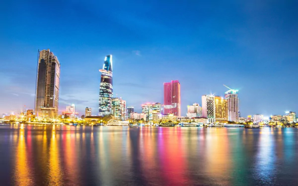 HD desktop wallpaper showcasing the vibrant skyline of Ho Chi Minh City, Vietnam, featuring the Bitexco Financial Tower and the shimmering Saigon River at dusk.