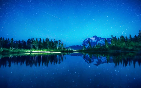 HD desktop wallpaper of a serene lake reflecting a starry night sky with a bright meteor streaking above, surrounded by trees and distant mountains.