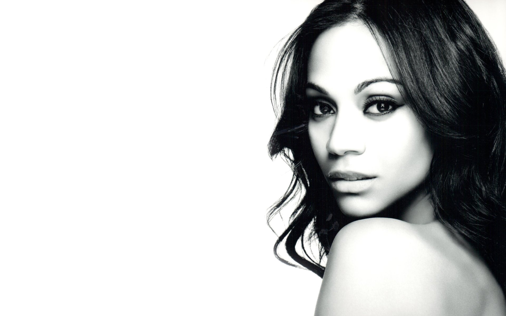 Black and white HD desktop wallpaper featuring American actress and celebrity Zoe Saldana with a soft, elegant expression and flowing hair.