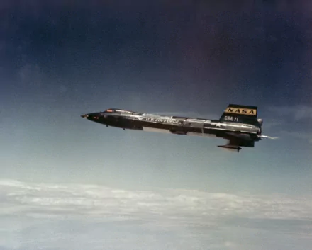 HD desktop wallpaper featuring the North American X-15 military rocket-powered aircraft soaring above the clouds against a clear sky background.