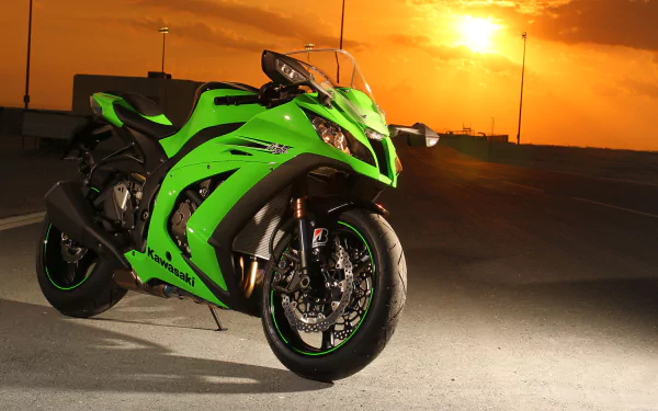 High-definition desktop wallpaper featuring a green Kawasaki Ninja motorcycle parked on a road with a dramatic sunset in the background.