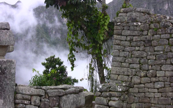 HD desktop wallpaper showcasing the man-made stone structures of Machu Picchu surrounded by mist and lush greenery.