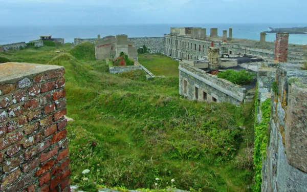 Fort Tourgis man-made coastal fort ruins with grassy earthworks and stone buildings by the sea — 2K Quad HD PC desktop wallpaper/background.