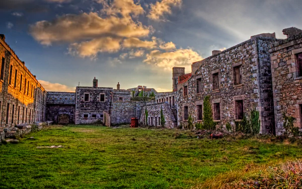HD desktop wallpaper of the man-made Fort Tourgis, showcasing historic stone buildings under a vibrant sky at sunset.